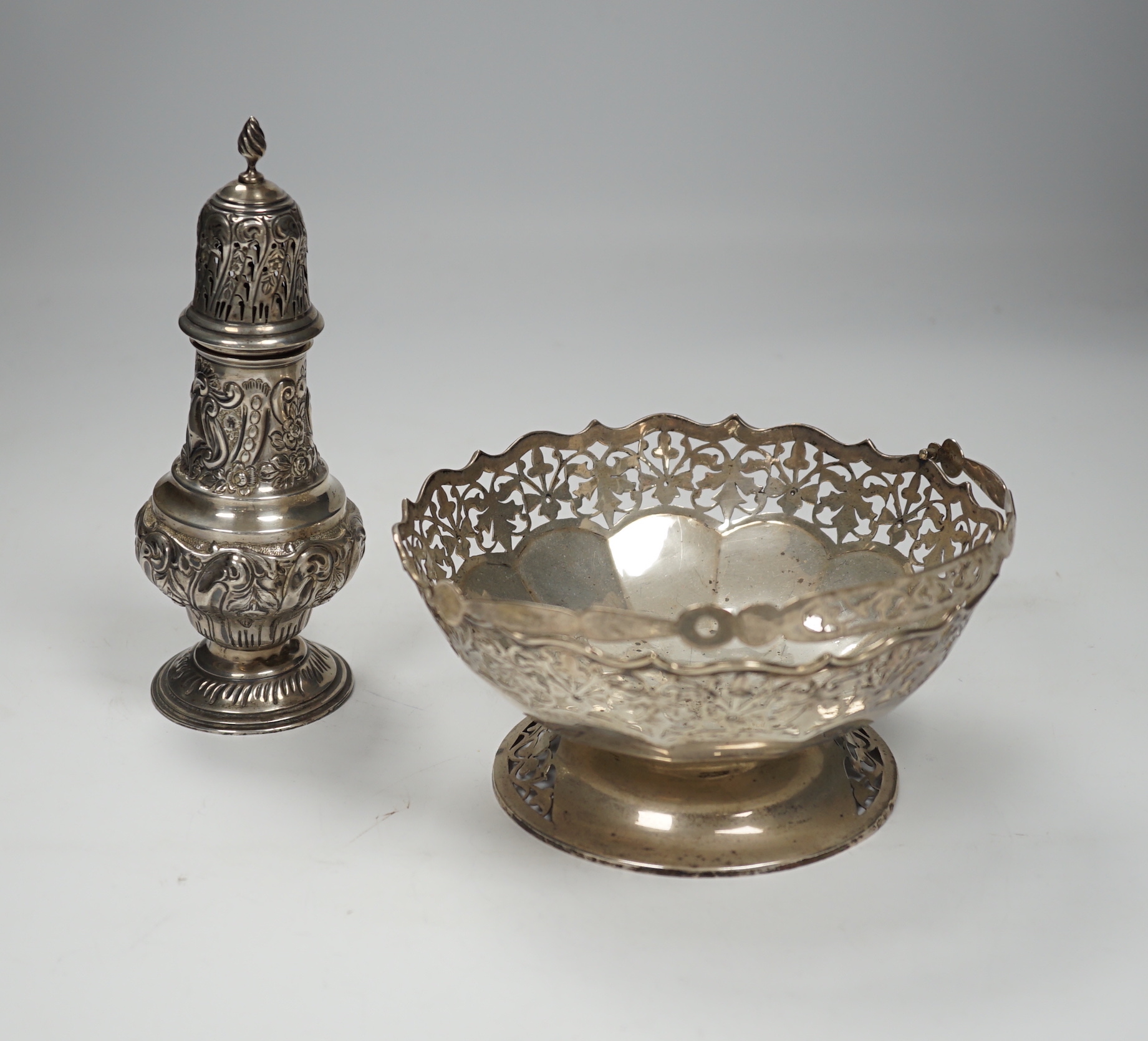 An Edwardian embossed silver sugar caster, Birmingham, 1904, 17.6cm and white metal cake basket stamped 'silver'.